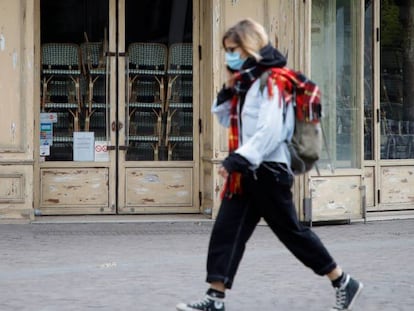 Una mujer pasea por París por delante de un restaurante cerrado.