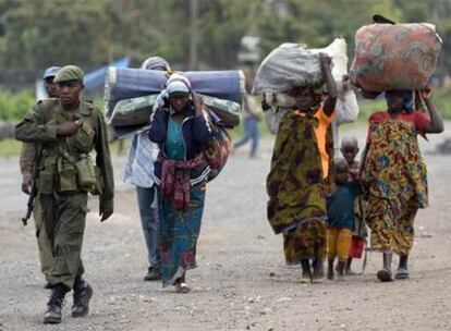 Un soldado congoleño camina junto a un grupo de desplazados en la ciudad de Goma.