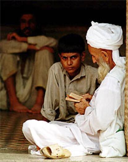 Un anciano con turbante lee ante un joven, en una madraza de Pakistán.