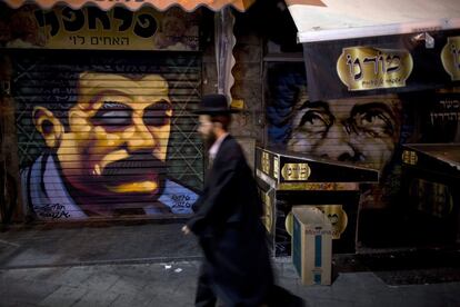 Un judío ultraortodoxo pasa delante de dos grafitis pintados por el artista callejero Solomon Souza en el mercado Mahane Yehuda.