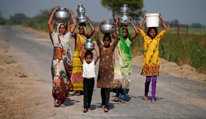 Mujeres y niñas indias transportan agua en las afueras de Ahmedabad el pasado sábado.