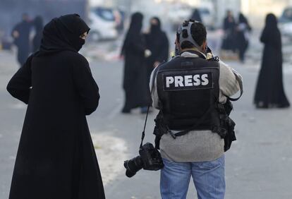 Una mujer observa como un fotógrafo realiza su trabajo durante una protesta en la localidad de Sanabis, al oeste de Manama.