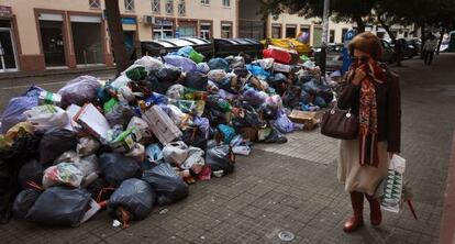 Una mujer se tapa la nariz al pasar junto a basura.