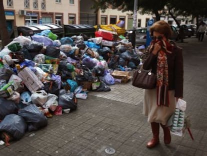 Una mujer se tapa la nariz al pasar junto a basura.