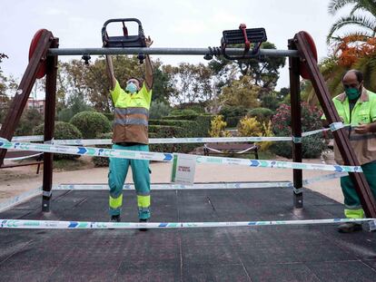 Varios operarios precintan unos columpios en un parque de Valencia el 18 de septiembre.