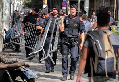 Agentes de los Mossos d'Esquadra transportan vallas para acordonar la zona del Parlament. 