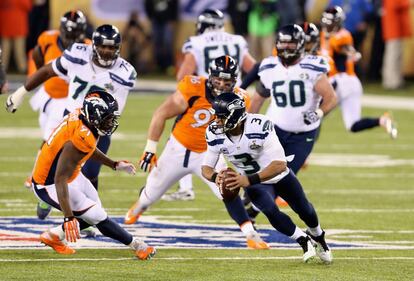 Russell Wilson, quarterback de Seattle, intenta zafarse de la defensa de Denver