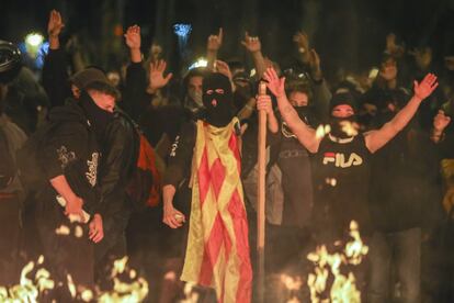 Un grupo de personas levanta los brazos frente a una hoguera, en una manifestación en la tercera jornada consecutivas de protestas, en Barcelona.