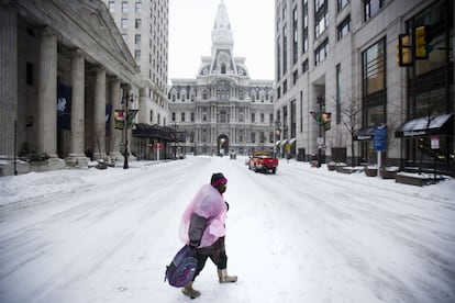 Una mujer camina por una calle nevada en Filadelfia (EE UU). Las tormentas de lluvia y nieve que azotan la costa este de Estados Unidos dejan un saldo de trece personas fallecidas en el sur del país, más de medio millón de personas sin electricidad, cerca de 4.500 vuelos cancelados, así como el cierre de escuelas y oficinas.