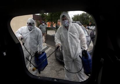 Dos empleados sanitarios desinfectan vehículos como medida preventiva para detener el avance del coronavirus, en Escobedo (México).