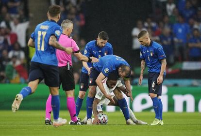 El inglés Raheem Sterling de rodillas, lucha por el balón con los italianos Giorgio Chiellini, Jorginho y Marco Verratti.