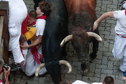 Varios mozos son aplastados contra una de las vallas al paso de los toros de la ganadería Cebada Gago, este lunes en Pamplona.
