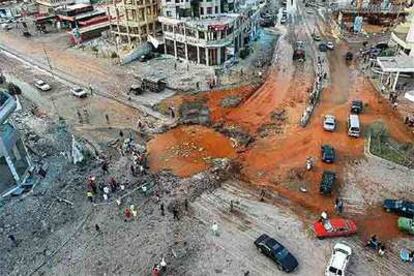 Ciudadanos libaneses se acercan a ver el cráter causado por una bomba israelí en una gran avenida del sur de Beirut.