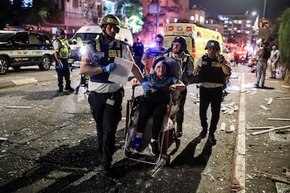 Personal de rescate evacua a una mujer herida en el lugar del impacto de un misil iraní contra Israel, en Ramat Gan.