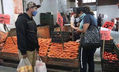 Dos personas con mascarillas compran en el Mercado de la Central de Abasto, en Ciudad de México.