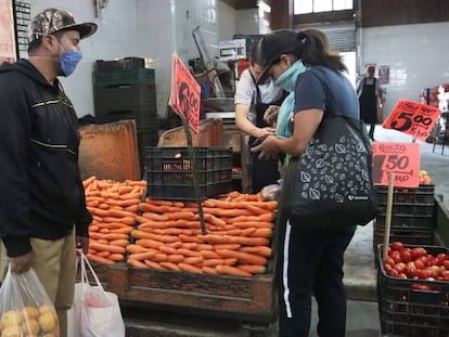 Dos personas con mascarillas compran en el Mercado de la Central de Abasto, en Ciudad de México.