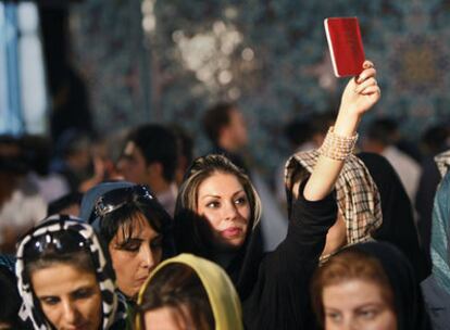 Una iraní enarbola su documento de identidad mientras espera para votar en la mezquita de Ershad, al noreste de Teherán.