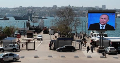 Una pantalla con una emisión de Vladímir Putin destaca sobre un puerto de Sevastopol, en Crimea.