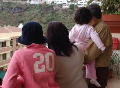 María, en brazos de su padre, y Clara, con gorra, junto a su madre en su casa de Tenerife.