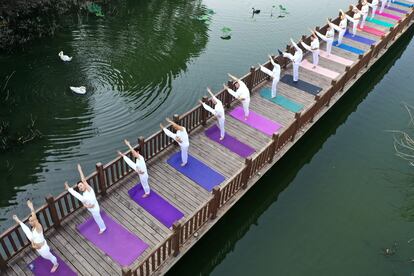 La India impulsa la práctica del yoga como una manera de combatir el impacto físico y emocional. En la imagen, clase de yoga sobre un puente en el parque de Handan, en la provincia china Hebei, el pasado lunes.