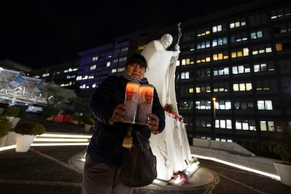 Una mujer sujeta dos velas con la imagen del Papa en el exterior del hospital Gemelli donde se encuentra ingresado, este martes. 