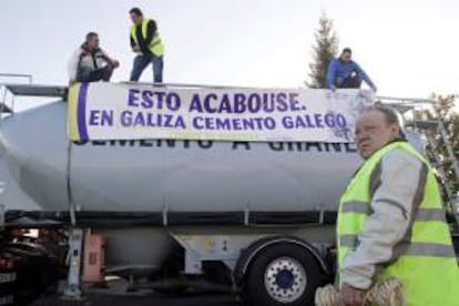 Varias personas colocan una pancarta en uno de los ochenta camiones que junto con decenas de turismos han tomado hoy Lugo en una peculiar forma de protesta en defensa de los puestos de trabajo de la fábrica que Cementos Cosmos tiene en Oural.