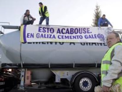 Varias personas colocan una pancarta en uno de los ochenta camiones que junto con decenas de turismos han tomado hoy Lugo en una peculiar forma de protesta en defensa de los puestos de trabajo de la fábrica que Cementos Cosmos tiene en Oural.