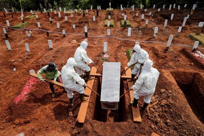 Varias personas con trajes aislantes entierran a una víctima de coronavirus en el cementerio de Pondok Ranggon en Yakarta, Indonesia.