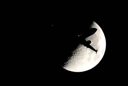 La silueta de un avión recortada contra la Luna en su aproximación al aeropuerto Internacional O'Hare en Chicago (EE UU).