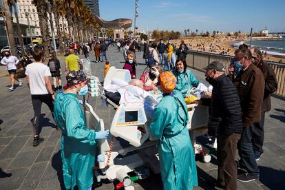 Un paciente con covid de 63 años, ingresado en el Hospital del Mar, sale al paseo marítimo acompañado por varios sanitarios en Barcelona.