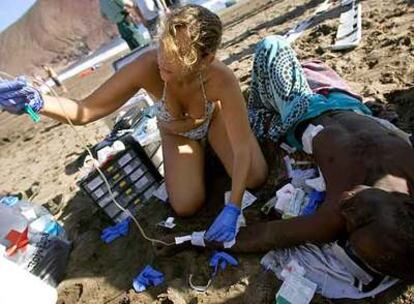 Una de las bañistas de la playa de la Tejita (sur de Tenerife) atiende a uno de los 43 subsaharianos llegados ayer.
