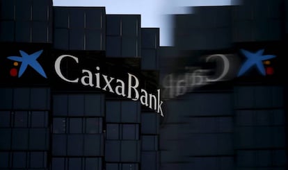 El logo de CaixaBank reflejado en el cristal de un cartel publicitario, en Barcelona.