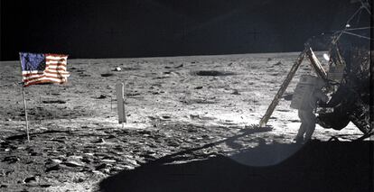 Neil Amstrong, junto al módulo lunar, con la bandera estadounidense clavada en el suelo lunar.