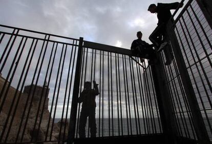 Jóvenes marroquíes, en la verja del espigón de Melilla.