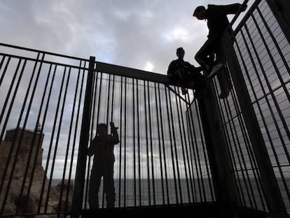 Jóvenes marroquíes, en la verja del espigón de Melilla.