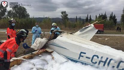 Varios bomberos junto a la avioneta accidentada en Vélez-Málaga.