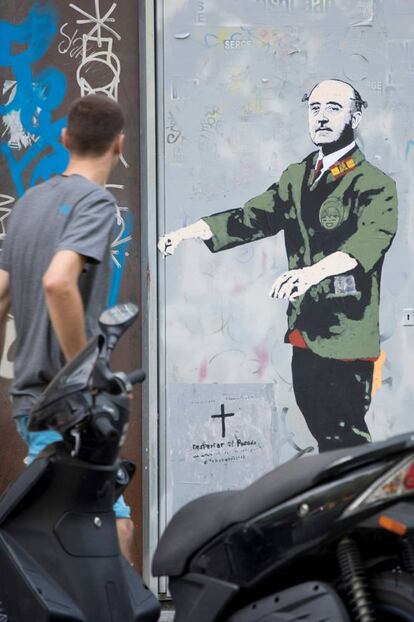 Un joven pasa ante un nuevo grafiti que firma el artista urbano TVBoy, aparecido hoy en la plaza Urquinaona de Barcelona, en el que se muestra al dictador Francisco Franco caracterizado como Frankenstein junto a una lápida en la que se puede leer "despertar el pasado".