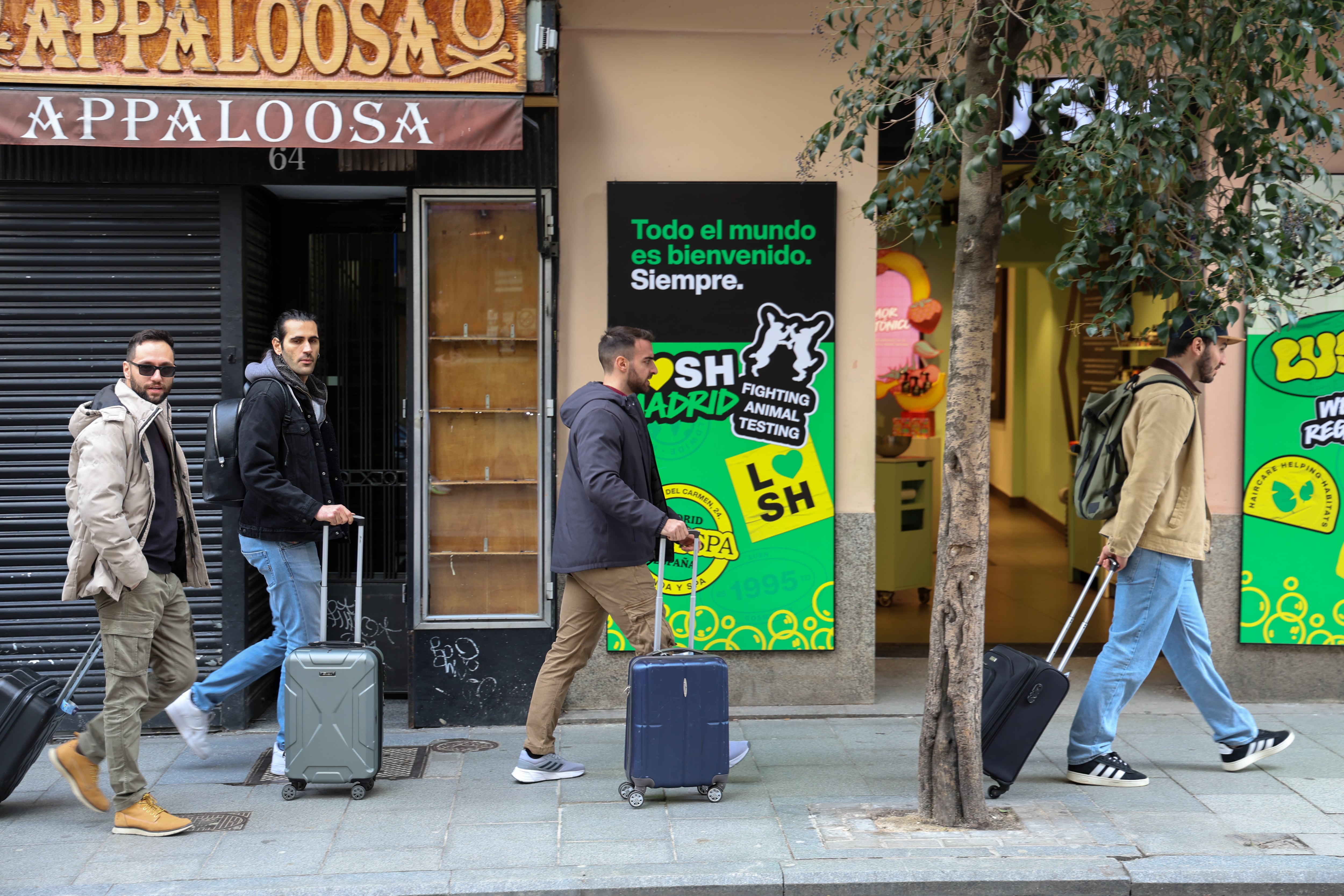 Cuatro turistas con sus maletas frente a un negocio de en cosmética natural en el barrio de Malasaña, Madrid, el 30 de enero de 2026. 