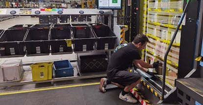 Un trabajador de Amazon introduce productos en las estanterías que le acercan los robots a su puesto de trabajo.