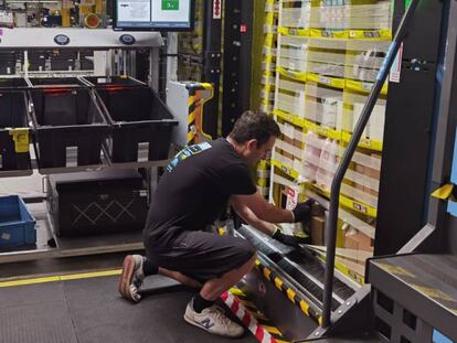 Un trabajador de Amazon introduce productos en las estanterías que le acercan los robots a su puesto de trabajo.