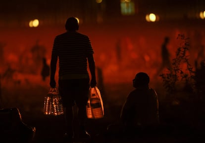 Un migrante carga agua cerca de la frontera con EE UU en Ciudad Juárez, este lunes.