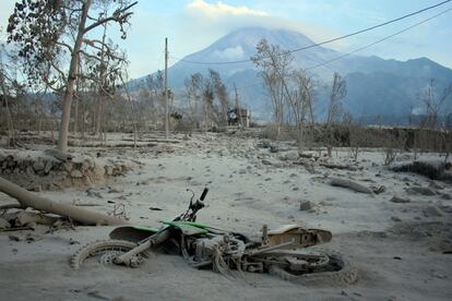 Una motocicleta, cubierta de lava en un pueblo cercano al monte Merapi (en el fondo de la fotografía).