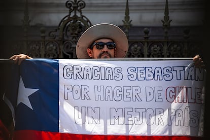 Un seguidor de Piñera sostiene una bandera chilena con la inscripción "Gracias Sebastián por hacer de Chile un mejor país", a las afueras de la antigua sede del Congreso.  