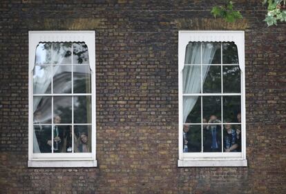 Unes persones miren a través de les finestres mentre esperen que la primera ministra, Theresa May, arribi al número 10 de Downing Street, a Londres.
