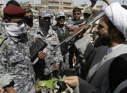 Policías iraquíes entregan sus armas a cambio de ejemplares del Corán al delegado de Al Sáder en Bagdad.