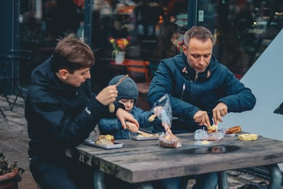 Dos padres comen con su hijo en su restaurante.