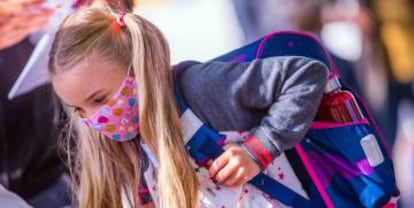 Una niña carga su mochila escolar.