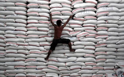 Un hombre trepa por unos sacos de arroz en un almacén gubernamental de Filipinas.