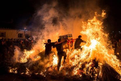 Cuatro hombres transportan un santuario antes de saltar un fuego durante las celebraciones de del Año Nuevo Chino, en Jieyang (China).