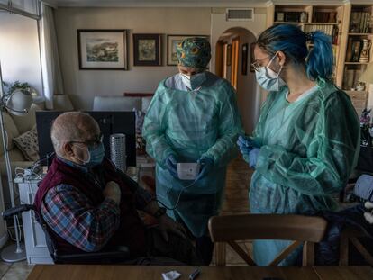 Las enfermeras Ana Fernández (con gorro) e Irene Ruiz, atienden a Eugenio Ramos, un enfermo crónico.